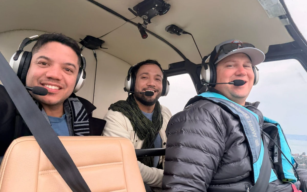 Ein Pilot und zwei Passagiere neben einem kleinen Flugzeug vor dem Einsteigen